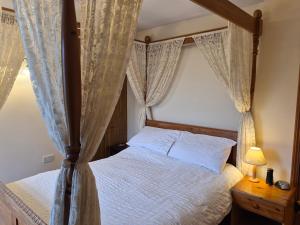 a bedroom with a four poster bed with curtains at Coastline cottage Pakefield, 2 minutes walk to the beach in Pakefield