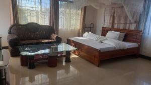 a bedroom with a bed and a chair and a coffee table at GcAnnexLodge in Iringa