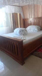 a wooden bed with two pillows on top of it at GcAnnexLodge in Iringa
