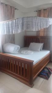 a large wooden bed with white sheets and pillows at GcAnnexLodge in Iringa