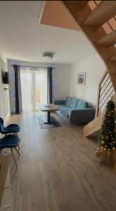 a living room with a blue couch and a christmas tree at Dwupoziomowe Apartamenty Leszczyna in Ustroń