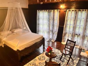 a bedroom with a bed and a chair and curtains at Greenbay Beach Resort in Varkala