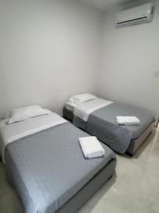 two beds in a white room with towels on them at Villa Sabanilla Casa bifamiliar campestre con piscina privada Aire acondicionado Tranquilidad total in Puerto Colombia +6 photos