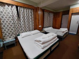 two twin beds in a room with curtains at Hotel Sunrise in Sāmthar +3 photos