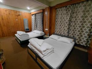 two beds in a room with wooden walls at Hotel Sunrise in Sāmthar