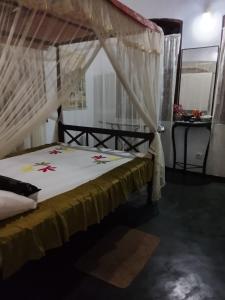 a bedroom with a bed with a mosquito net at peacock Rest in Batapola