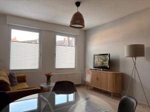 a living room with a couch and a tv and two windows at BrunnenApart Nova in Bad Oeynhausen
