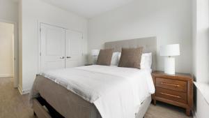 a white bedroom with a large bed and a nightstand at Landing Apartments - Prospect Hall in Frederick +14 photos