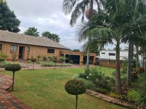 a yard with palm trees and a building at A Pearl Place in Pretoria
