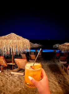a person holding a drink on a beach at night at Villa Maximos in Episkopí