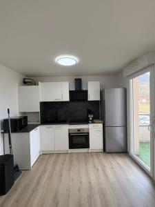 a kitchen with white cabinets and a stainless steel refrigerator at Appartement T2 Confort in Albertville