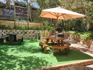 a patio with a table and benches and an umbrella at Log Cabin- Forest, Lagoon Sea location in Hermanus