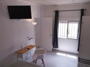 a bedroom with a bed and a desk and a television at Toscana Apartamentos in Progreso