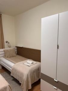 a bedroom with a bed and a white cabinet at Emma Apartman 2 in Vecsés