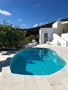 a swimming pool in front of a white house at Villa Mikro Chorio in Kóstos
