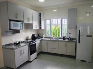 a kitchen with white cabinets and a white refrigerator at Casas Bela Vista 1 - 2 in Águas de Lindoia