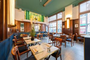 a restaurant with tables and chairs and windows at Grand Hôtel de Valenciennes in Valenciennes