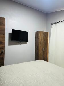 a bedroom with a bed and a flat screen tv on a wall at Epic Arenal View House in Fortuna
