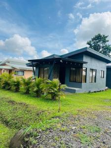 a blue house with a grass yard in front of it at Epic Arenal View House in Fortuna