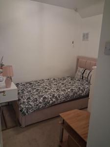 a small bedroom with a bed and a table at Cullen Sqaure in South Ockendon