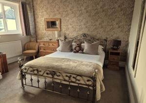 a teddy bear sitting on a bed in a bedroom at Denehurst Guest House - Adults Only in Windermere