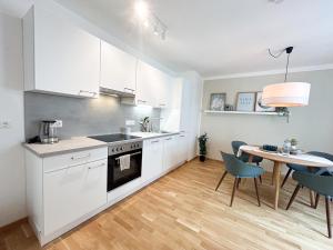 a kitchen with white cabinets and a table with chairs at Ruhiger Familientraum fürs Wochenende oder längerfristigen Aufenthalt in Wiener Neustadt