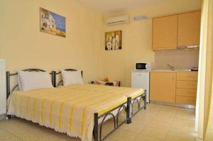 a bedroom with a bed with a yellow and white blanket at Nestor Apartments in Chrysi Ammoudia