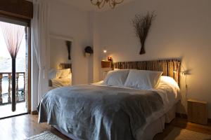 a bedroom with a bed with white sheets and a window at Casa Prada en Sanabria in Puebla de Sanabria