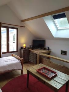 a bedroom with a bed and a table and a television at Le refuge in Montabon