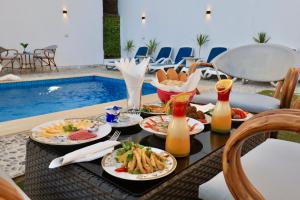 a table with plates of food and drinks next to a pool at White Gorf Hotel in Luxor