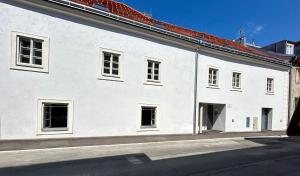 a white building with windows on a street at Ruhiger Familientraum fürs Wochenende oder längerfristigen Aufenthalt in Wiener Neustadt