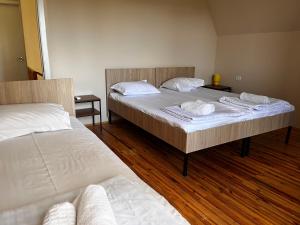 two beds in a room with wooden floors at Dali`s Guest House in Lebach'e