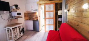 a living room with a red couch and a kitchen at L'Escale Balnéaire Landaise in Biscarrosse-Plage