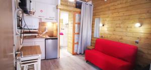 a living room with a red couch and a kitchen at L'Escale Balnéaire Landaise in Biscarrosse-Plage