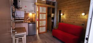 a living room with a red couch and a kitchen at L'Escale Balnéaire Landaise in Biscarrosse-Plage