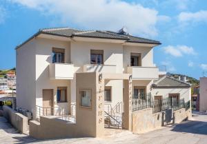 a white house with a black roof at Sirens Resort in Agioi Apostoli