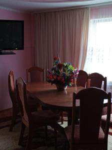 a dining room table with a vase of flowers on it at Ольга in Ogrody