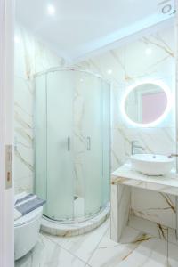 a white bathroom with a shower and a sink at Sirens Resort in Agioi Apostoli +22 photos