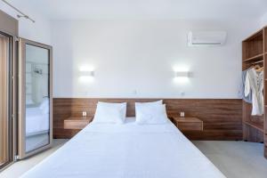 a bedroom with a white bed and a mirror at Sirens Resort in Agioi Apostoli