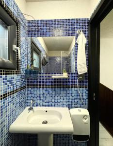 a blue tiled bathroom with a sink and a mirror at RestOnTheLake in Esztergom +28 photos