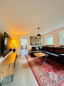 a living room with a black leather couch and a rug at Lichtdurchflutetes Souterrain Apartment in Schapen in Braunschweig