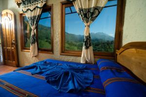 a bedroom with a blue bed with a view of mountains at El Mirador de Lanquin in Lanquín