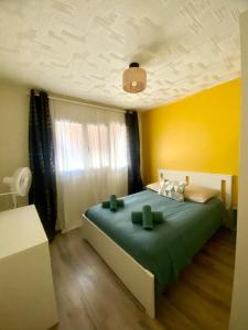 a bedroom with a green bed with a yellow wall at Appartement T3 avec grand balcon in Le Pradet