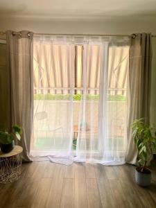 a large window with white curtains in a room at Appartement T3 avec grand balcon in Le Pradet +2 photos