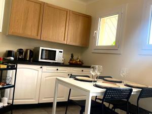 a kitchen with a white table with chairs and a microwave at Appartement T3 avec grand balcon in Le Pradet