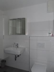 a white bathroom with a sink and a toilet at Apartment Vlora-Naturblick in Villach +3 photos