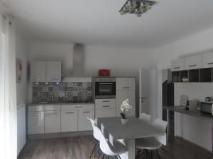 a kitchen with white cabinets and a table with white chairs at Apartment Vlora-Naturblick in Villach