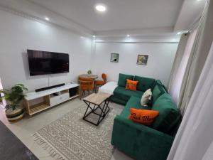 a living room with a green couch and a television at Waridi Homes One-bedroom Naivegas Apartment in Naivasha