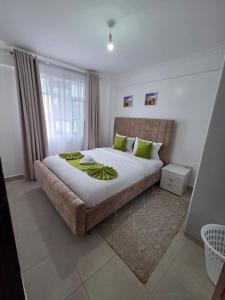 a bedroom with a large bed with green pillows at Waridi Homes One-bedroom Naivegas Apartment in Naivasha