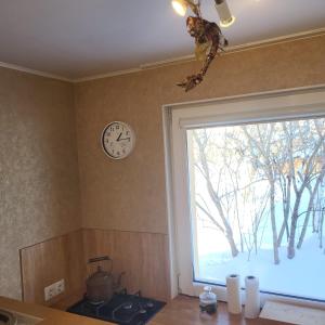 a kitchen with a clock on the wall and a window at House with a fireplace in Daugavpils